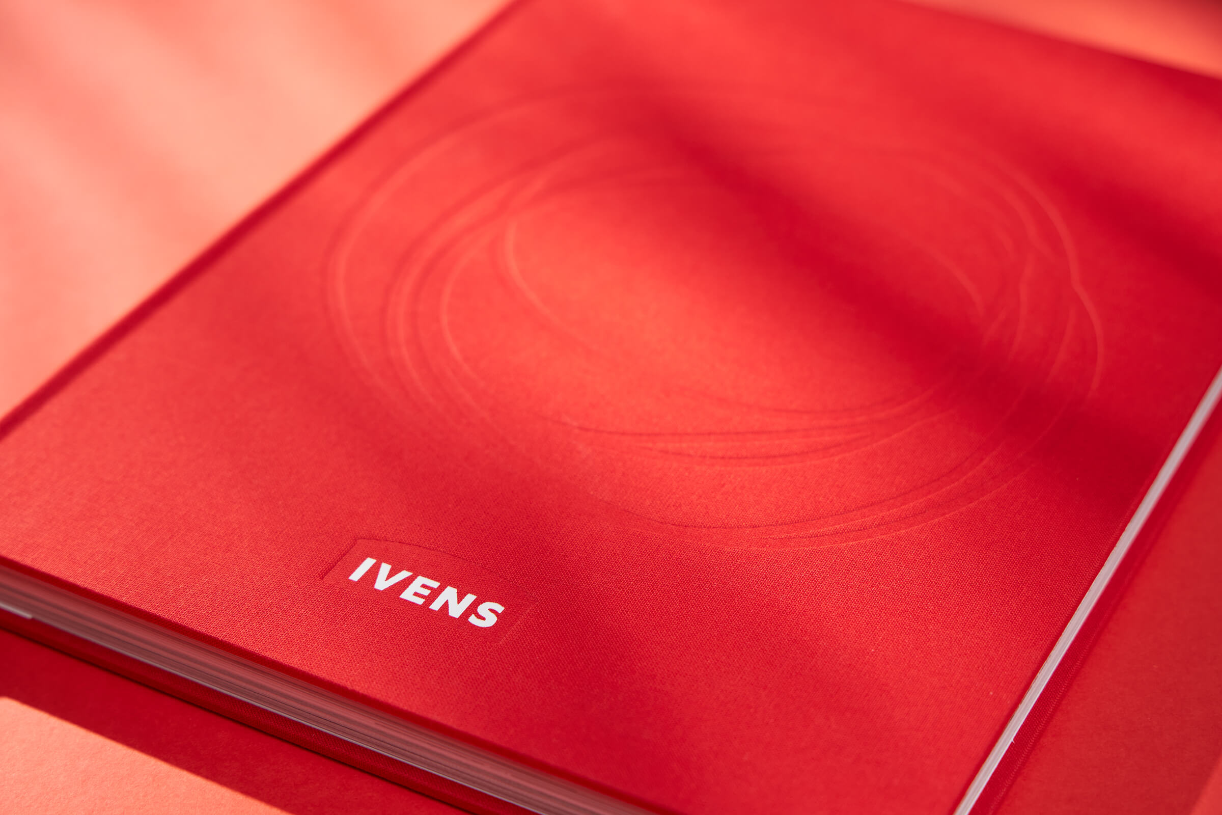 jubileumboek ivens met witte foliedruk en blinddruk op een rode linnen cover